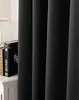 A close-up view of black curtains, with a bedside table and books visible on the left. Produktbild-Vorschau