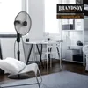 A modern living room or office space with a stand fan, desk, chair, and shelving unit. Voir les images du produit