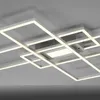 A modern, geometric LED ceiling light fixture with multiple intersecting rectangular frames, mounted on a light gray ceiling. Produktbild-Vorschau