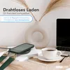 A desk scene with a phone on a wireless charger, a cup of coffee, a laptop, and a vase with dried flowers. Produktbild-Vorschau