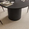 A close-up view of a round dining table with a fluted base, set with plates and cutlery on a textured rug. Produktbild-Vorschau