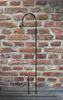 A black metal shepherd's hook garden stake stands vertically against a brick wall. Produktbild-Vorschau