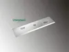 A single metal blade with two holes and a circular indentation, placed diagonally on a gradient background. A green logo with text is visible in the upper left corner. Náhled obrázku produktu