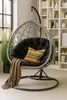 A hanging egg chair with a cushion and throw blanket is placed in a room with a bookshelf in the background. Anteprima dell’immagine prodotto