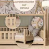 Close-up view of a wooden children's bed with decorative wallpaper and pillows. Produktbild-Vorschau