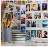 A collection of instant photos displayed on a wall, with makeup brushes and notebooks in the foreground. Produktbild-Vorschau