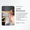 A young woman is holding a box of cutlery in a kitchen setting. Produktbild-Vorschau