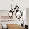 A modern kitchen and dining area with a bicycle-shaped pendant light hanging above a wooden table. Podgląd zdjęcia produktu