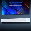 A white soundbar is mounted on a dark blue wall below a television screen displaying abstract art and text. Produktbild-Vorschau