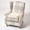 A wingback armchair with a tartan pattern and a cream cushion on the seat. Náhled obrázku produktu