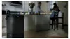 A kitchen scene with people in the background and an air purifier in the foreground. Produktbild-Vorschau