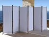 A white fabric room divider is set up outdoors on a patio with a view of the ocean. Produktbild-Vorschau