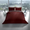 A bed with bordeaux and anthracite bedding is set up in a modern room with large windows overlooking a landscape. Produktbild-Vorschau