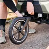 A person is shown adjusting the wheel of a bicycle trailer. Produktbild-Vorschau