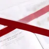 A close-up view of a red ribbon draped over what appears to be a wedding invitation or announcement. Produktbild-Vorschau