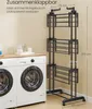 A black drying rack is shown next to two washing machines in a laundry room. Produktbild-Vorschau