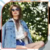 A young woman wearing a denim jacket and shorts, posing outdoors. Produktbild-Vorschau