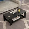A black coffee table with a laptop, a cup of coffee, and a small vase of yellow flowers on top, placed on a patterned rug next to a sofa. Produktbild-Vorschau