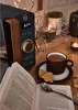 A cozy scene with a microwave, a cup of tea, cookies, and an open book. Náhled obrázku produktu