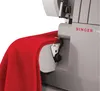 A close-up view of a red fabric being fed into a sewing machine. Náhľad obrázku produktu