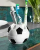 A soccer ball-shaped toothbrush holder with toothbrushes and toothpaste on a counter. Produktbild-Vorschau