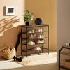 A shoe rack with shoes, an umbrella, a bag, and a plant in a room. Náhled obrázku produktu
