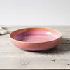 A pink and orange iridescent bowl sits on a wooden table. Náhled obrázku produktu