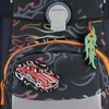 Close-up of a backpack with flame-like patterns and attached accessories. Voir les images du produit