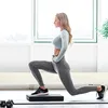 A woman is performing a lunge exercise on a balance pad in a bright room. Podgląd zdjęcia produktu