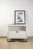 A white nightstand with a drawer and an open shelf, decorated with a framed black and white photograph and a mug. Podgląd zdjęcia produktu