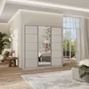 A bedroom scene featuring a large sliding door wardrobe with mirrored panels, set against a backdrop of a window with greenery visible outside. The wardrobe is the central focus, with a bed and other bedroom furniture suggested in the reflection and surrou Produktbild-Vorschau