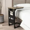 A bedside table with integrated charging ports and storage pockets is placed next to a bed. Produktbild-Vorschau