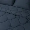 A close-up view of a dark blue comforter with a hexagonal quilting pattern. Produktbild-Vorschau