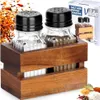 A set of salt and pepper shakers in a wooden holder, with packaging in the background. Náhľad obrázku produktu