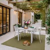 An outdoor patio dining area with a table set for a meal, a cat sleeping on a rug. Produktbild-Vorschau