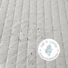 A close-up of a quilted fabric surface with water droplets, featuring a circular marketing badge. Produktbild-Vorschau