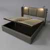 A modern upholstered bed frame with its storage compartment open and the slatted base lifted, revealing the storage space underneath. Two small reading lights are attached to the headboard. Náhled obrázku produktu