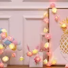 A string of rose-shaped LED lights draped around a framed picture and a decorative tree with cotton balls. Produktbild-Vorschau
