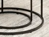 Close-up of a black metal table base on a rug. Podgląd zdjęcia produktu
