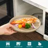 A hand is placing a plate of food into a microwave. Náhled obrázku produktu