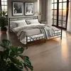 A bedroom scene with a metal bed frame, bedding, and decor. Náhled obrázku produktu