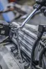 A gloved hand uses a socket wrench to tighten a spark plug on an engine. Anteprima dell’immagine prodotto