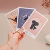 A hand holding three spiritual message cards with animal illustrations and text. Voir les images du produit