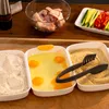 A setup for breading chicken, showing raw chicken pieces, flour, eggs, and breadcrumbs in separate containers, along with sliced vegetables. Náhľad obrázku produktu