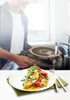 A person is washing a pan in a sink, with a plate of food in the foreground. Produktbild-Vorschau