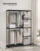 A black metal garment rack with various clothes and folded items on shelves, set against a light gray wall and white curtains. Produktbild-Vorschau