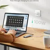 A person's hands are using a laptop connected to a USB-C hub, which is also connected to a power adapter plugged into the wall. The hub is on a wooden desk. Produktbild-Vorschau