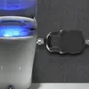 A close-up shot of a modern toilet with a blue light emanating from the lid, connected to a black device on a textured gray wall. Náhled obrázku produktu