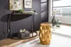A gold honeycomb-patterned stool is placed next to a console table in a room with a dark gray wall and a large window. Produktbild-Vorschau