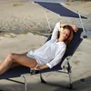 A woman relaxing on a blue lounge chair on a sandy beach. Náhled obrázku produktu
